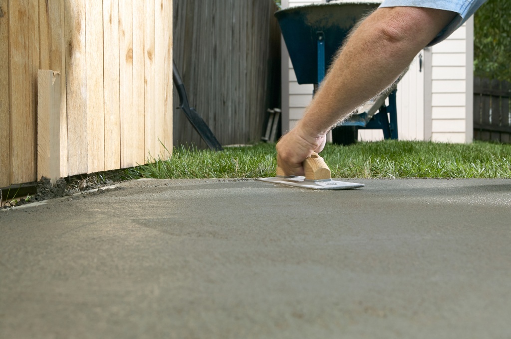 Person finishing wet cement with concrete screed