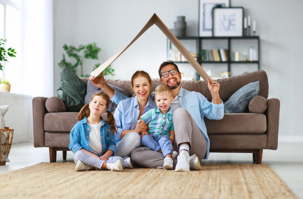 concept of housing and relocation. happy family mother father and kids with roof at home