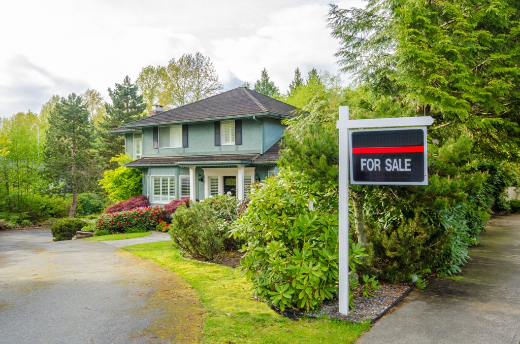 House For Sale Real Estate Sign in Front of a House.