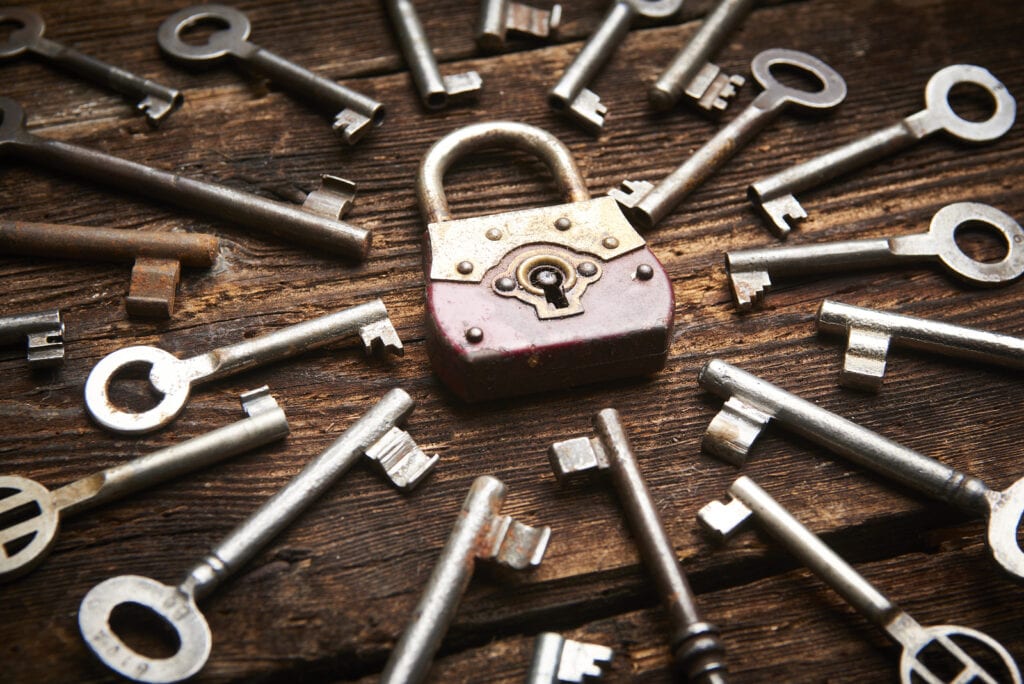 Vintage rusty padlock surrounded by old keys on a weathered wooden background