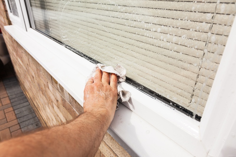 Man wiping down window sill that has been cleaned with soapy water