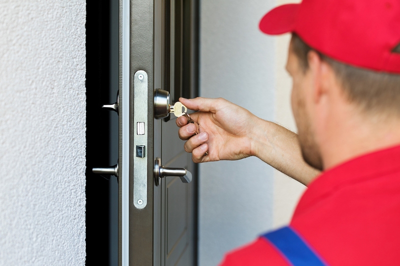 door lock service – locksmith working in red uniform