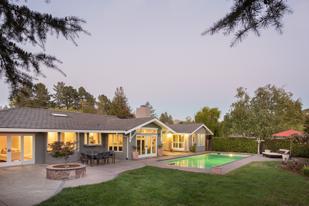 Luxury home with swimming pool at sunset with outdoor furniture.