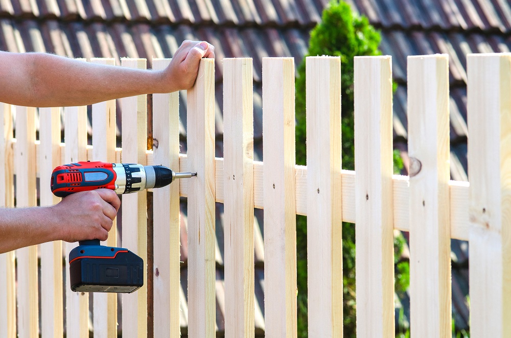 building a wooden fence with a drill and screw. Close up of his