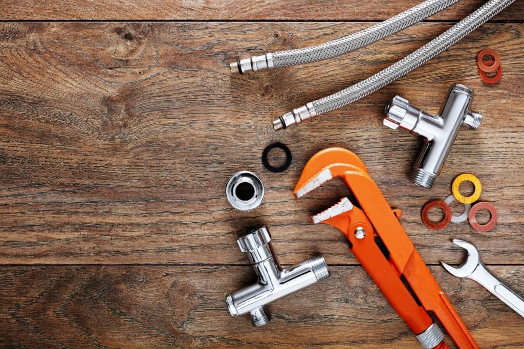 Set of plumbing tools on wooden table background.