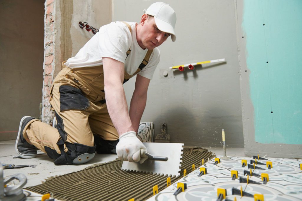 Tiler installing tile on bathroom floor. home indoors renovation