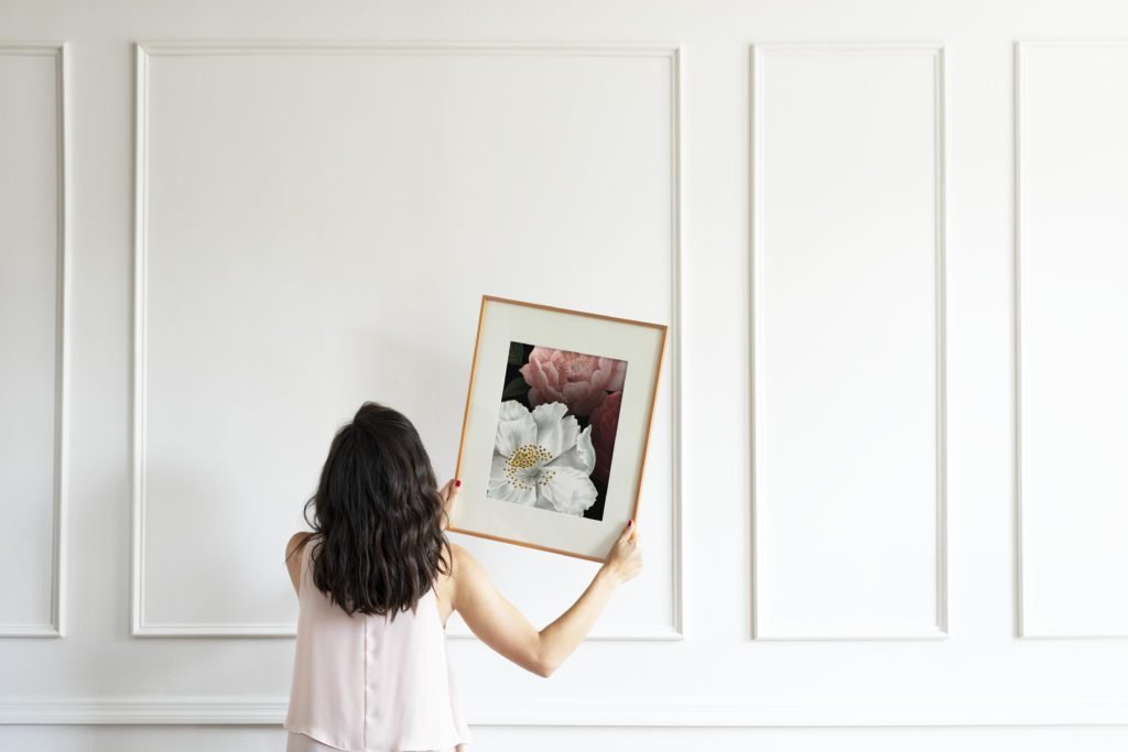 Woman hanging a frame on a white wall