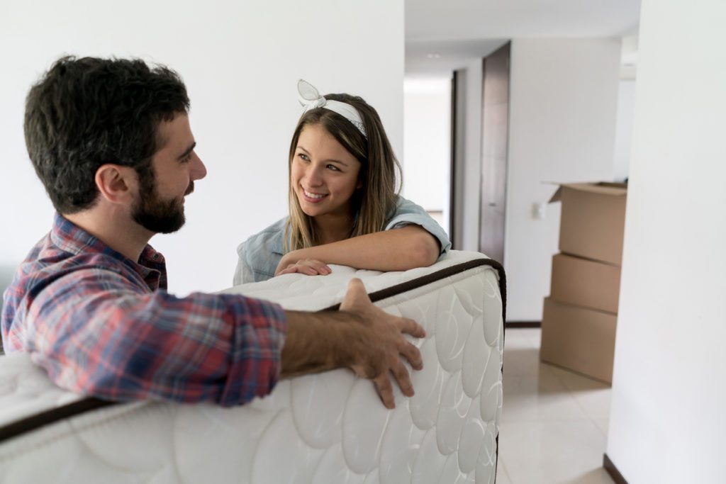Playful woman with her partner while he is moving in a matress into their new place