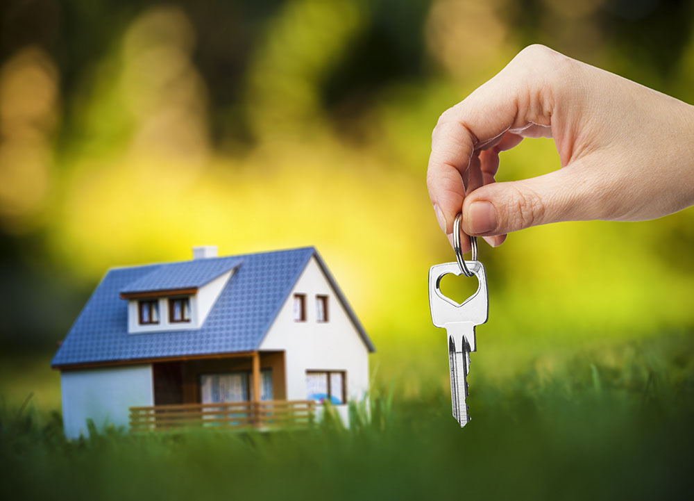 hand holding key against house background