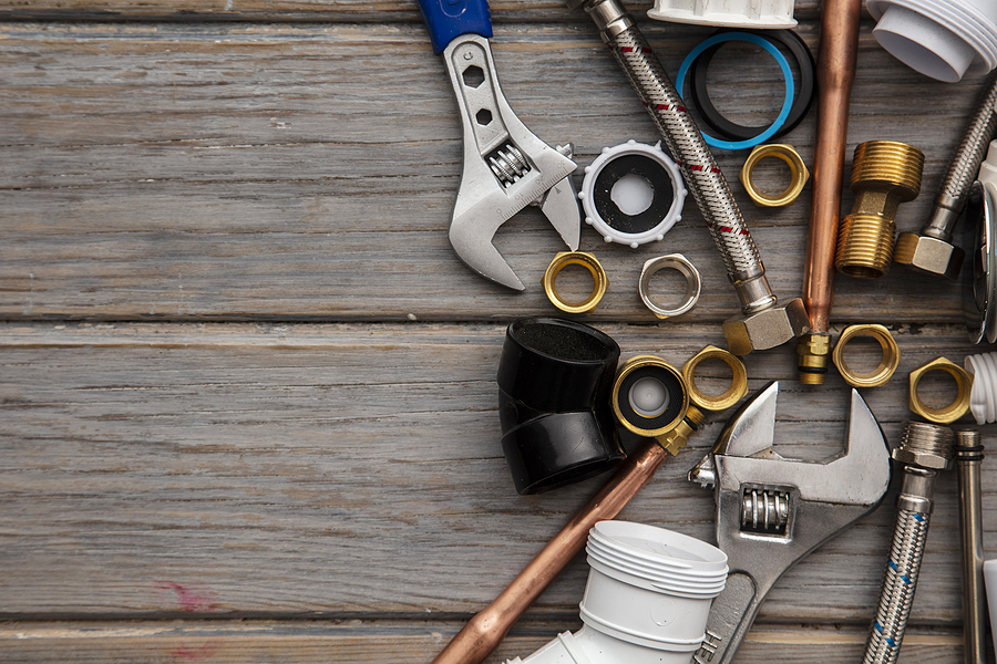 Plumbing Tools, Pipe And Fixings On A Rustic Wooden Background.