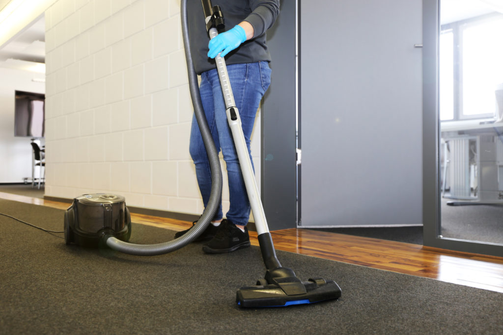 Office cleaning: Cleaner vacuums the corridor of an office
