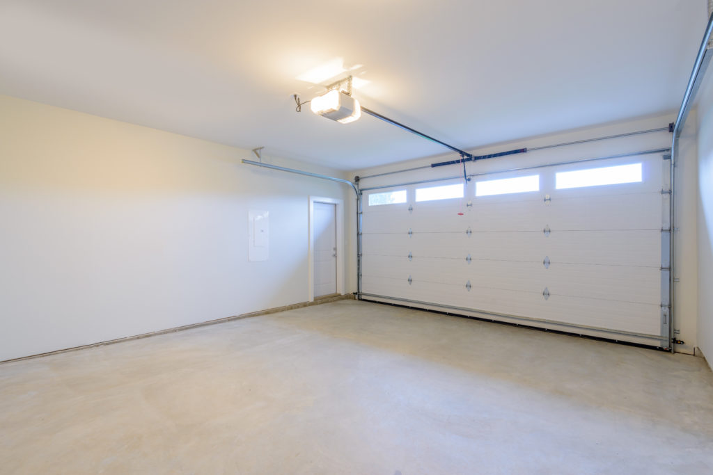 An empty garage with door and windows.