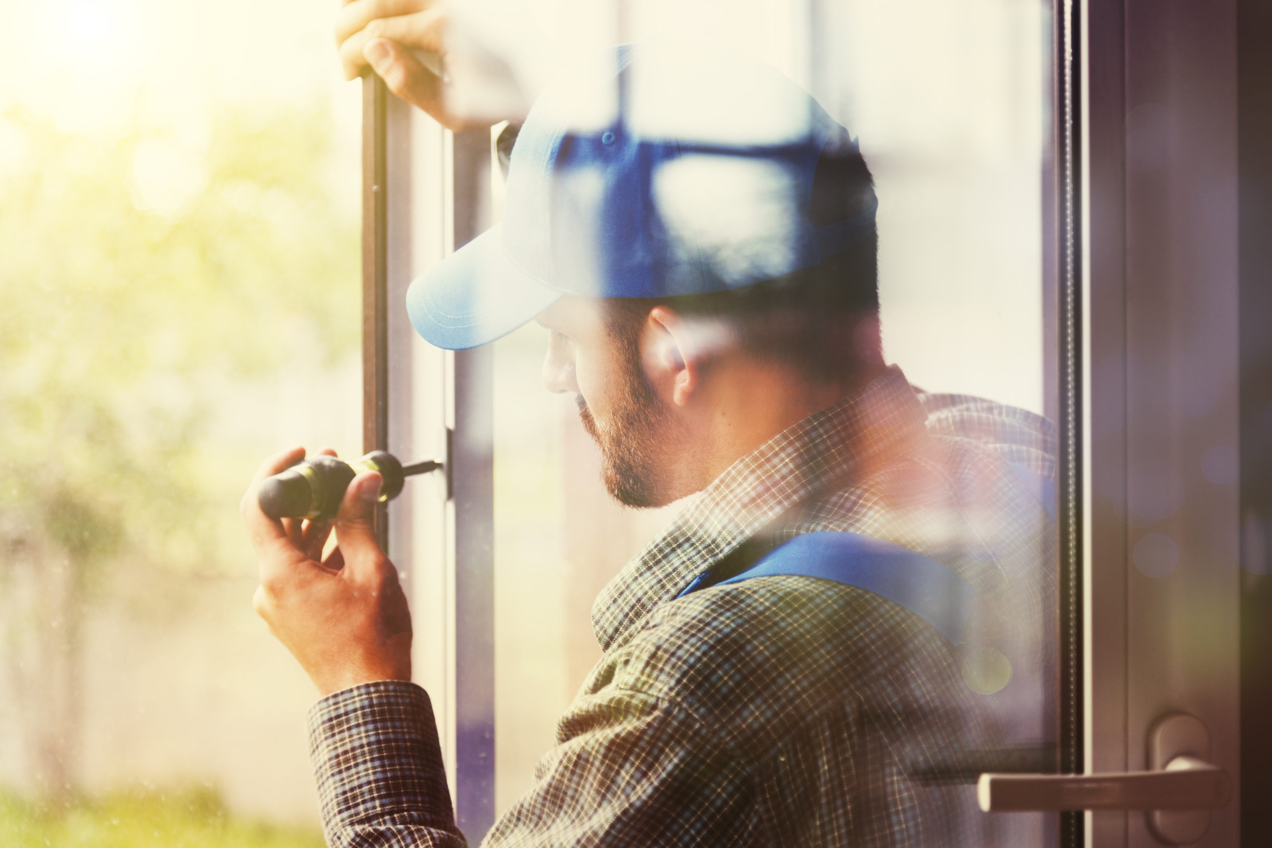 service man installing window with screwdriver