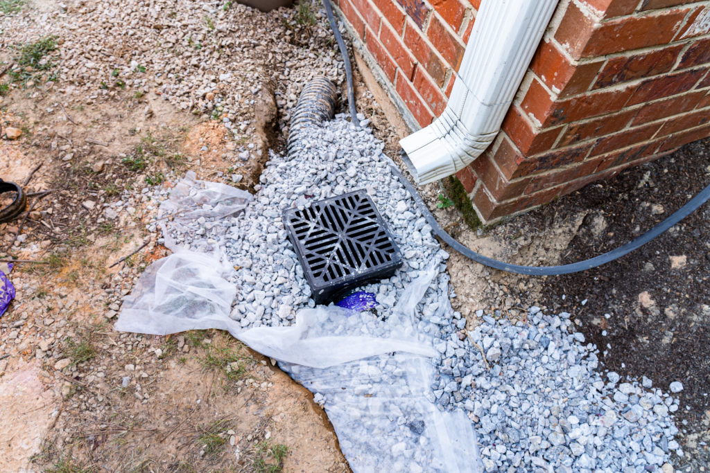 Plastic catch basin installed under a downspout to alleviate dra