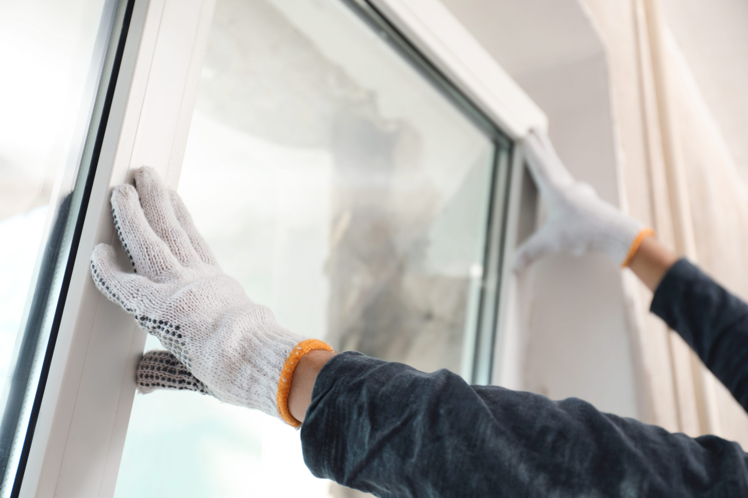 Worker installing plastic window indoors, closeup view