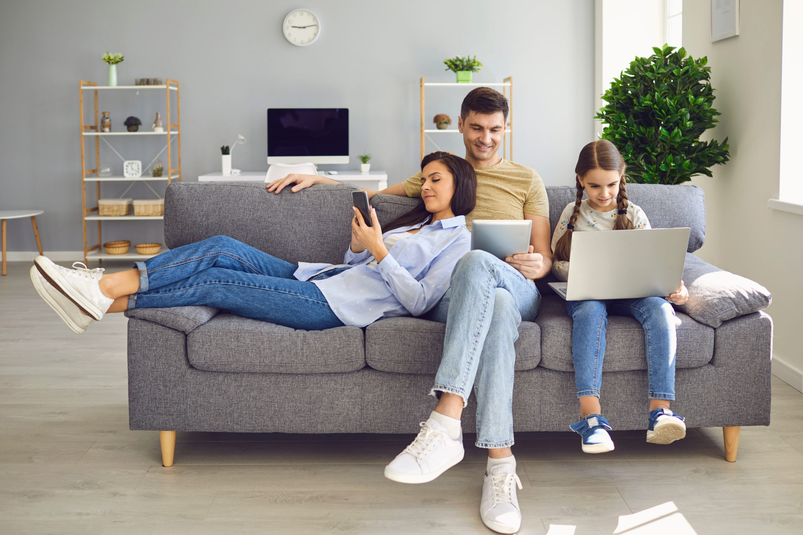 Parents and a kid child look at a laptop at their leisure in a weekend at home