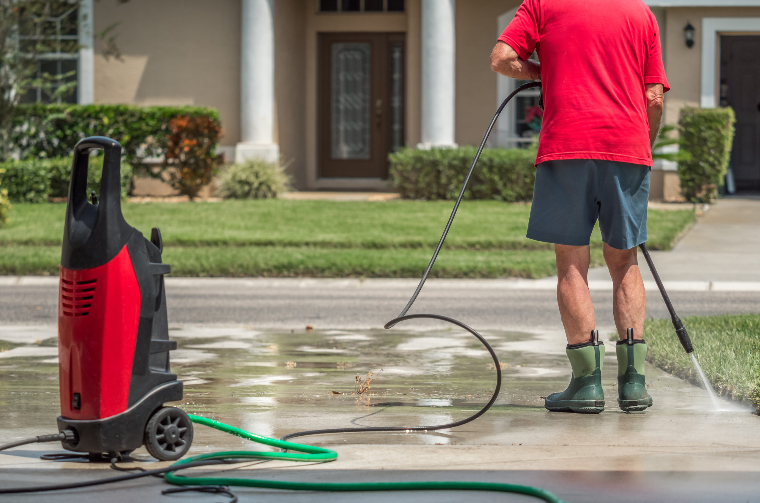 Man using electric powered pressure washer to power wash residen
