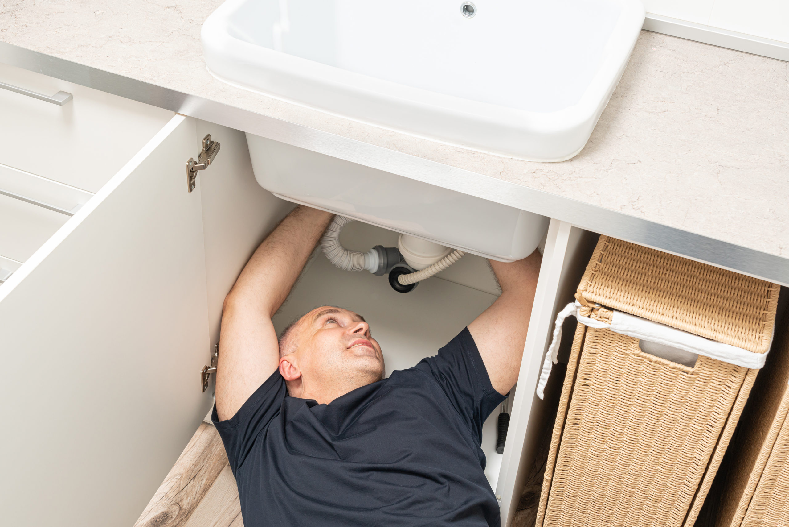 top view of repairing plumbing by a man under the sink