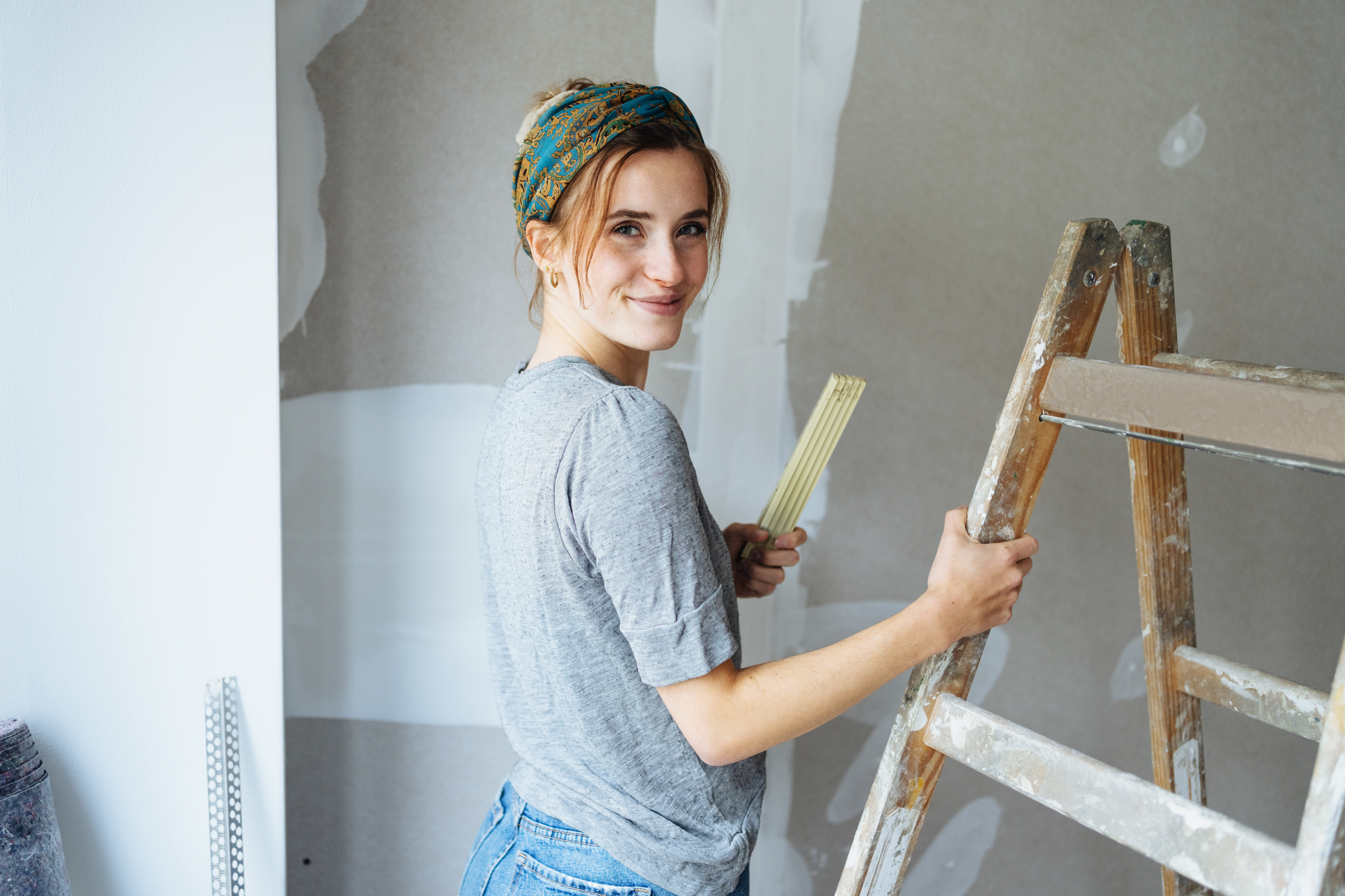Young woman renovates her apartment and looks at the camera