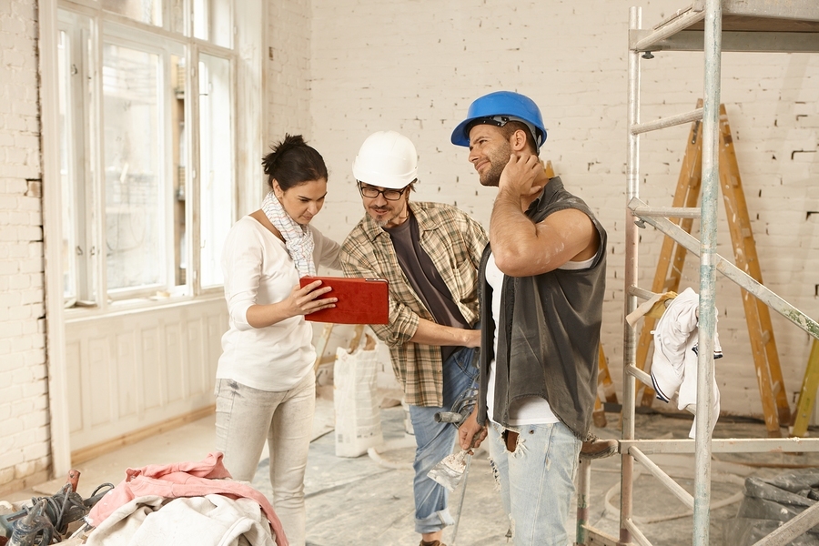 Female client showing plans on tablet computer to contractors, s