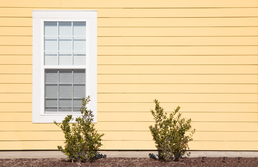 One solitary window on the exterior of a house with bright yello