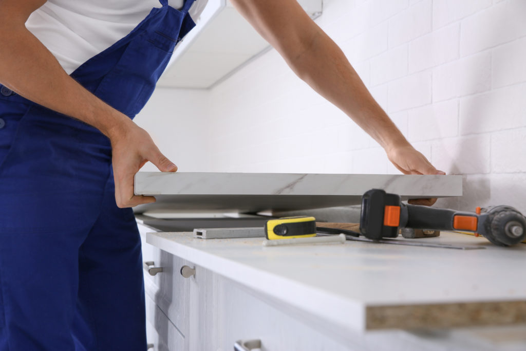 Worker installing new countertop in kitchen, closeup