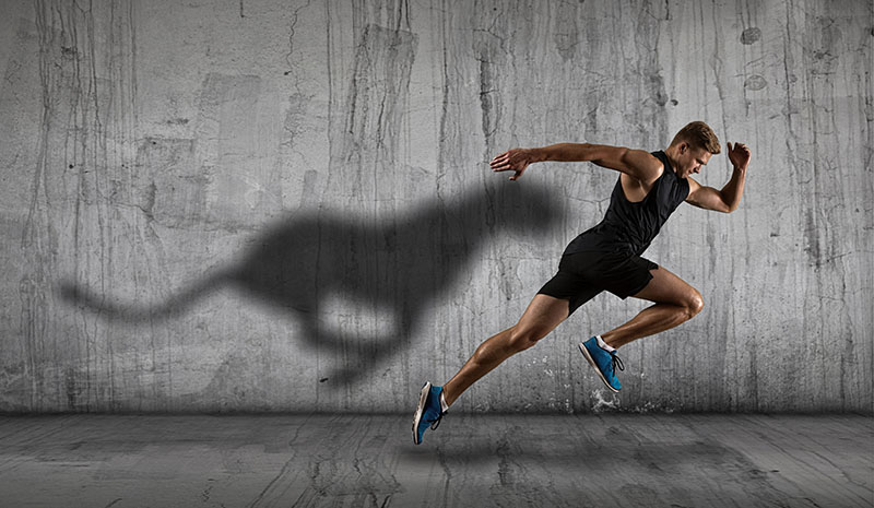 Athletic man sprinter running on dark wall background