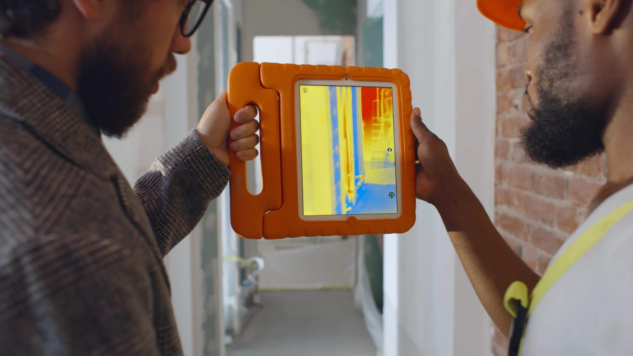 Back view of professional construction team using infrared camera on tablet checking heating system