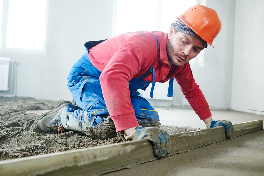 worker screeding indoor cement floor with screed