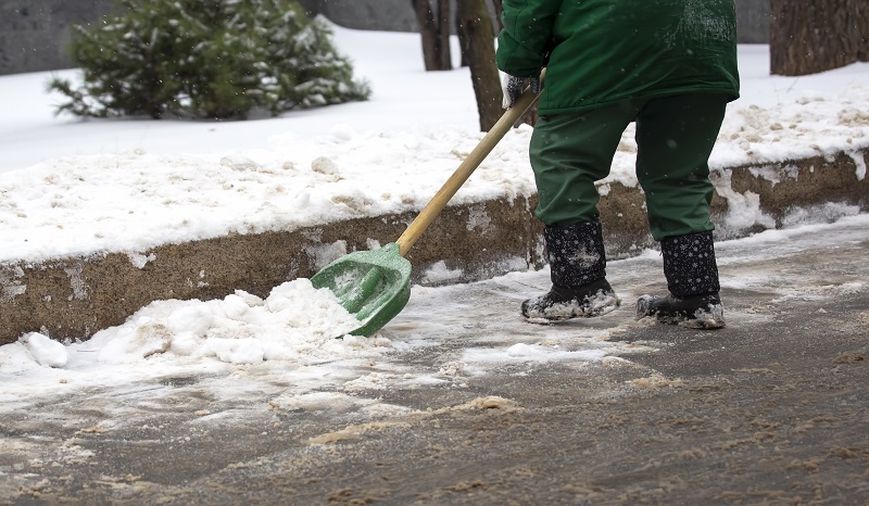 street worker shovels snow from the sidewalk