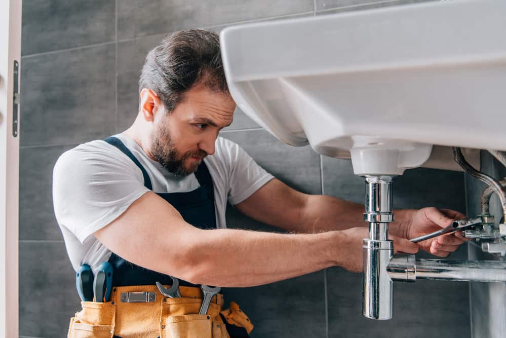 Focused-male-plumber-in-working-overall-fixing-sink