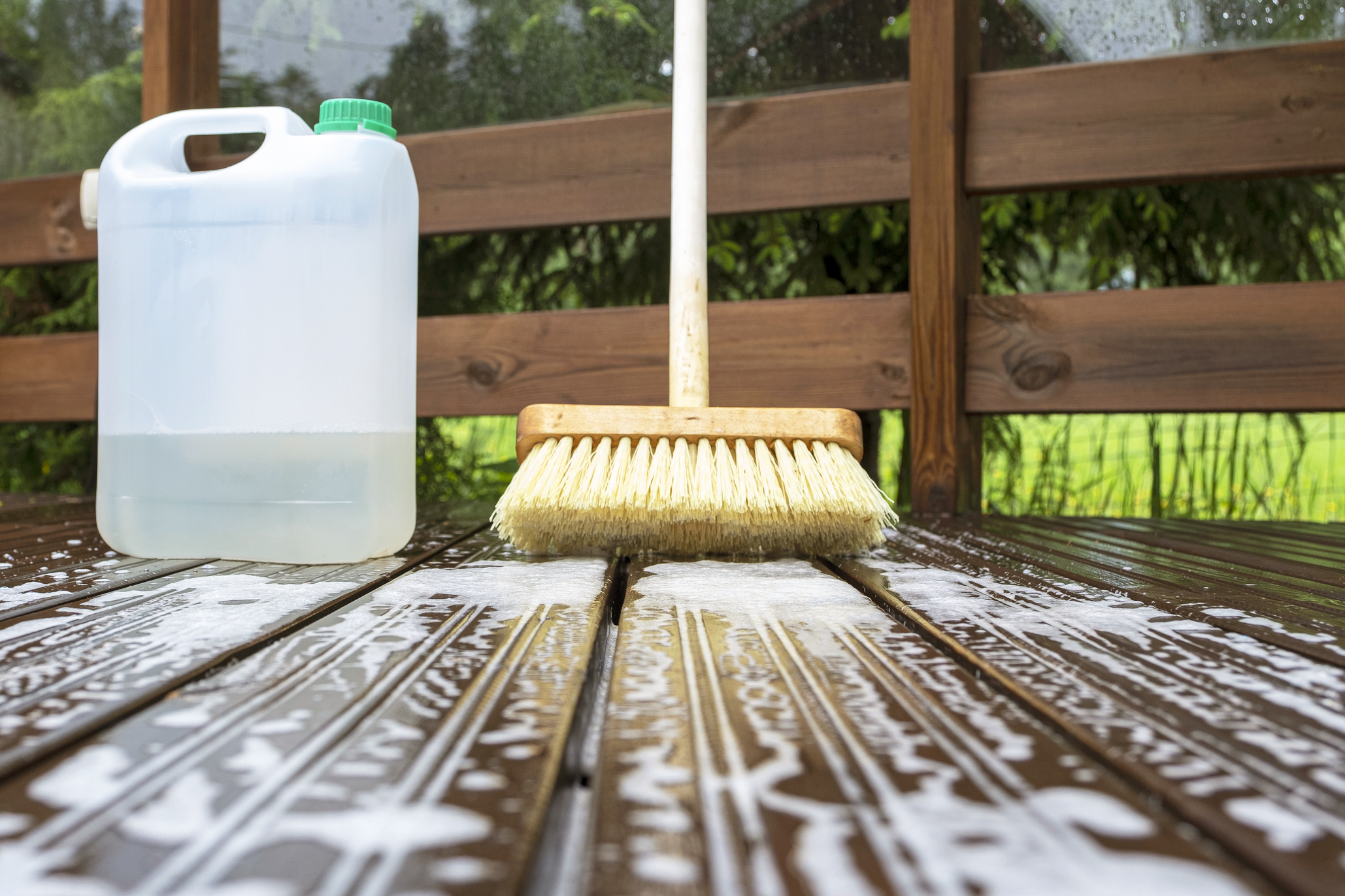 Brush, plastic canister with mortar and soapy water on wooden terrace boards