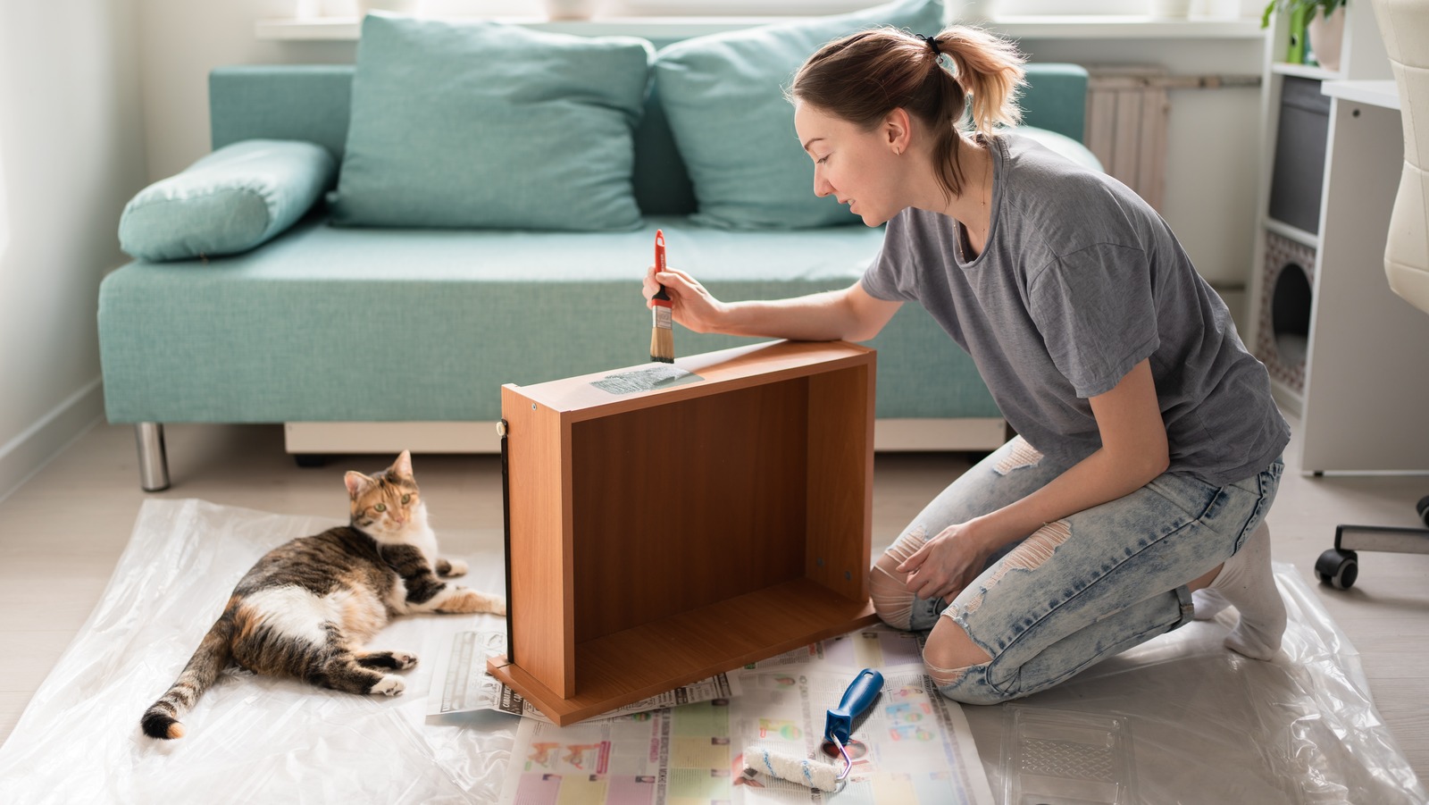 Young,Woman,Painting,Drawer.,Cat,Lying,Nearby.,Furniture,Repair.,Do