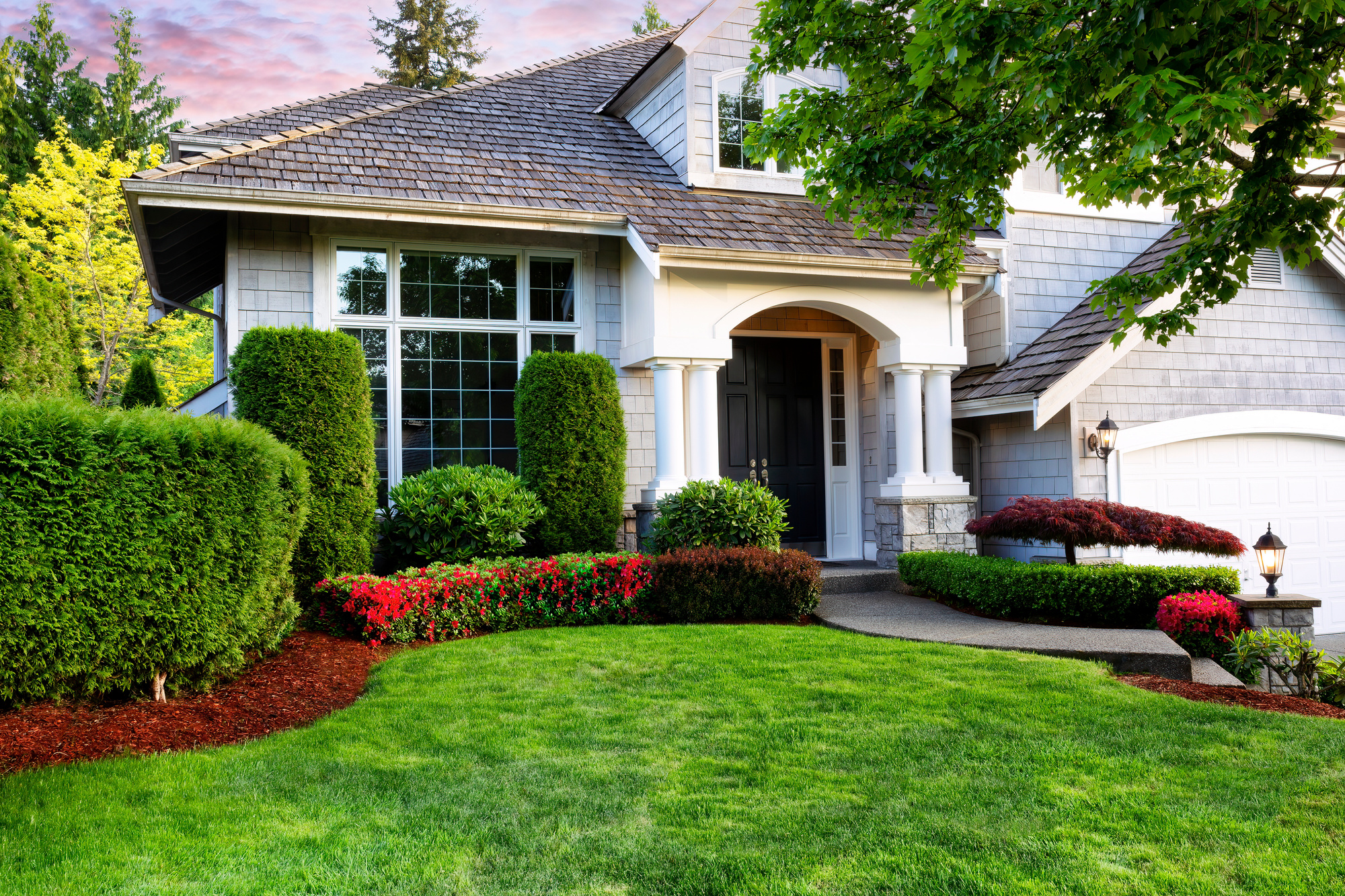 Beautiful home exterior in evening with healthy green lawn and f