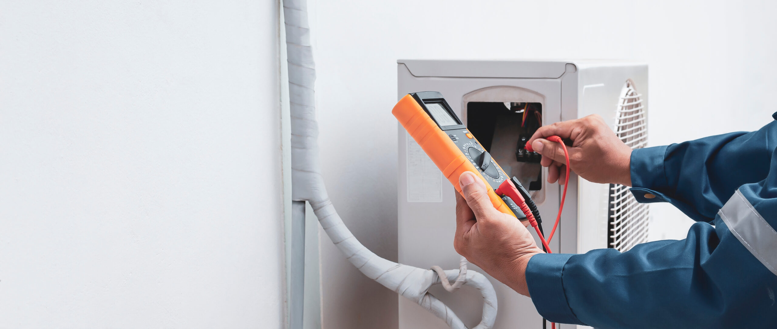 Repairman holding multimeter to check air conditioner system
