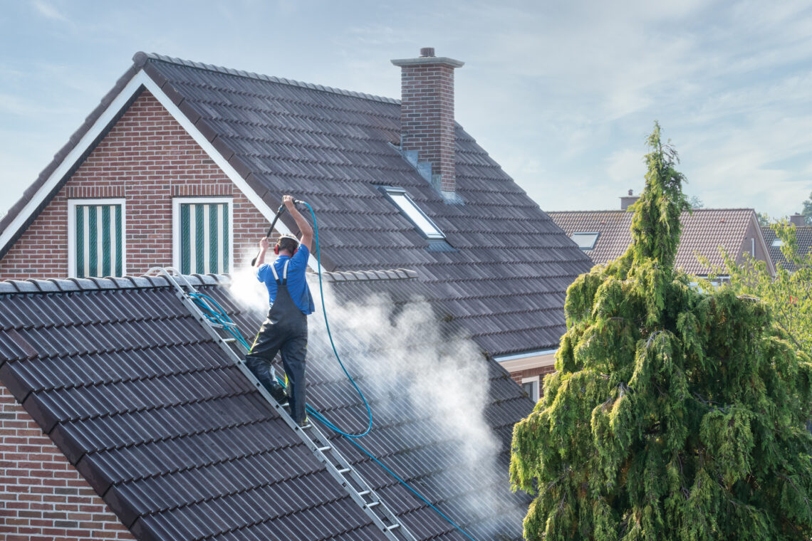 Cleaner with pressure washer at roof house cleaning roof tiles