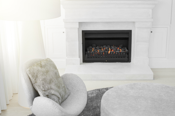 Modern chair and floor lamp next to marble fireplace in living room