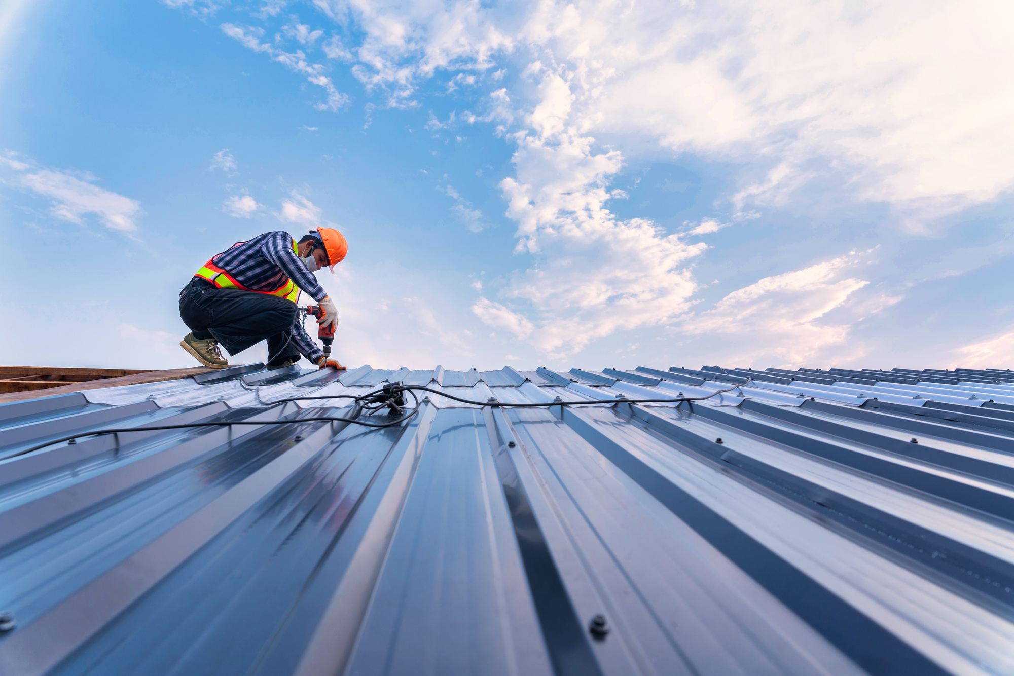 Roof construction concept, Roofer using air or pneumatic nail gu