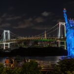 Odaiba Statue of Liberty Replica surrounded by lights with the Rainbow Bridge on the background