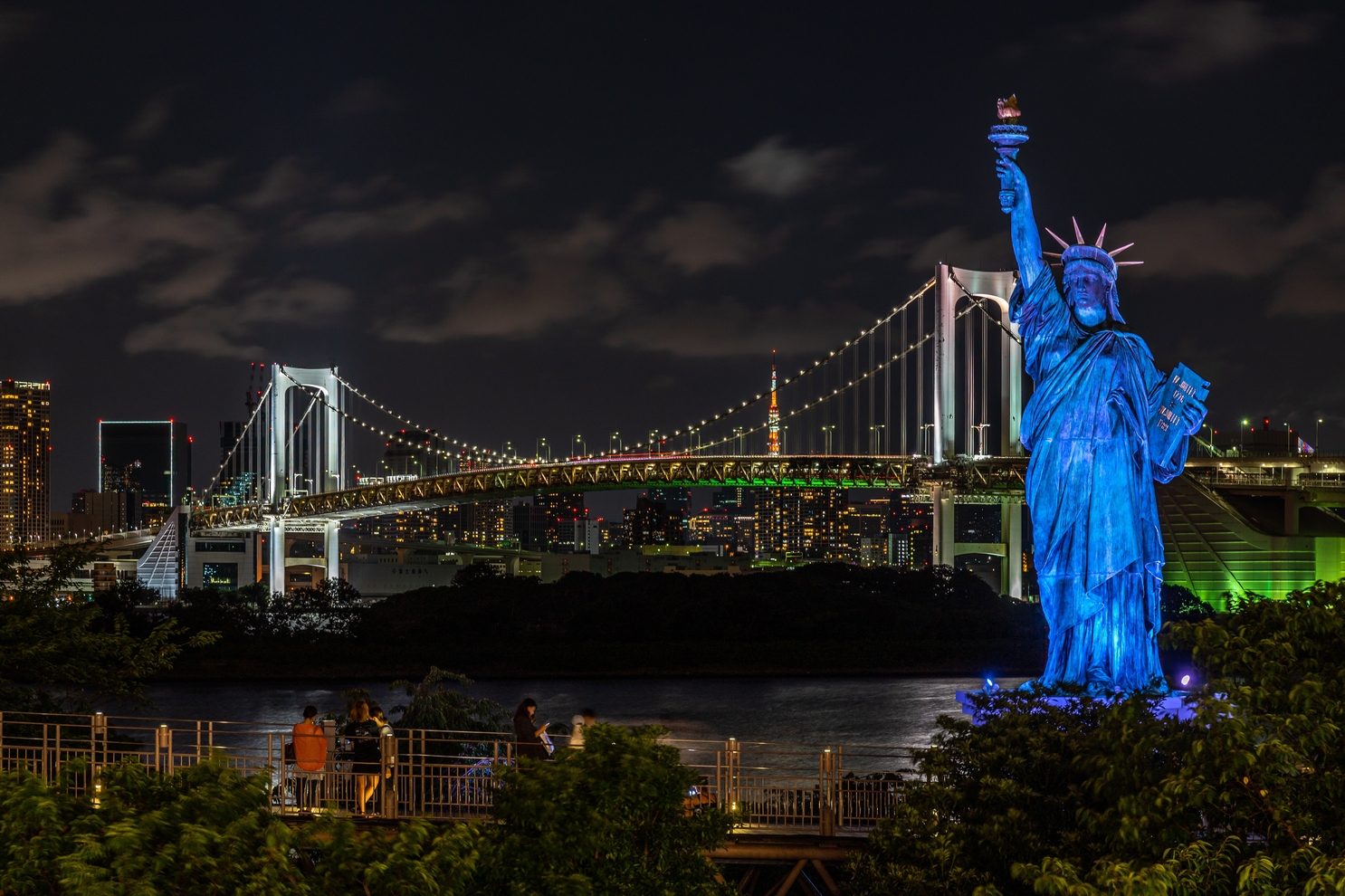 Odaiba Statue of Liberty Replica surrounded by lights with the Rainbow Bridge on the background