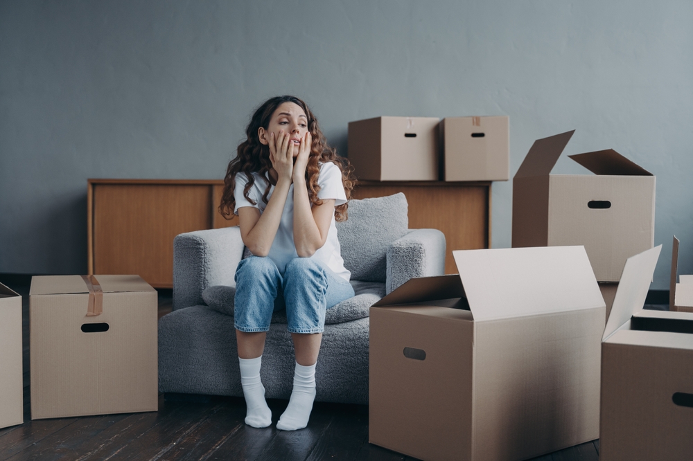 Tired,Young,Woman,Sitting,Near,Cardboard,Boxes,On,Relocation,Day,